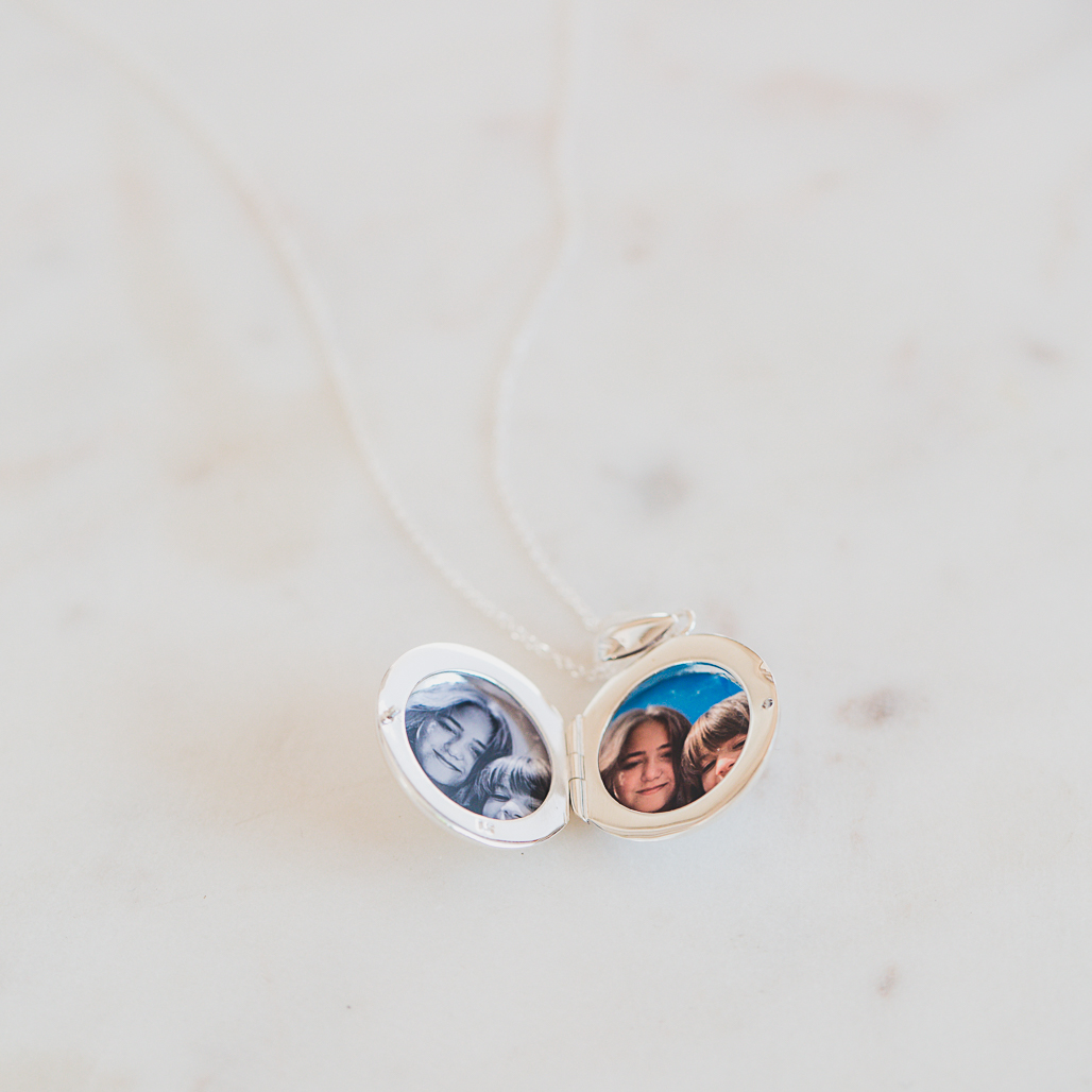 medium silver round locket that holds two photographs in color and black and white
