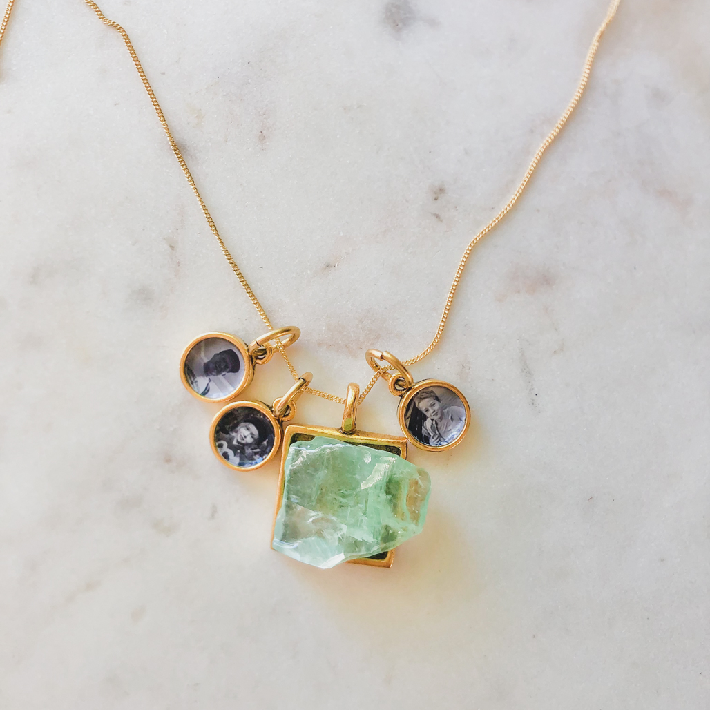 emerald calcite gemstone pendant with three photo locket pendants in gold adjacent