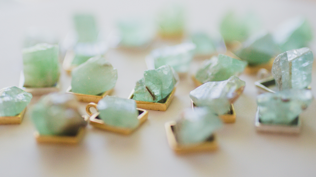 emerald green calcite pendants that are bulky in square gold pendants on a white backdrop