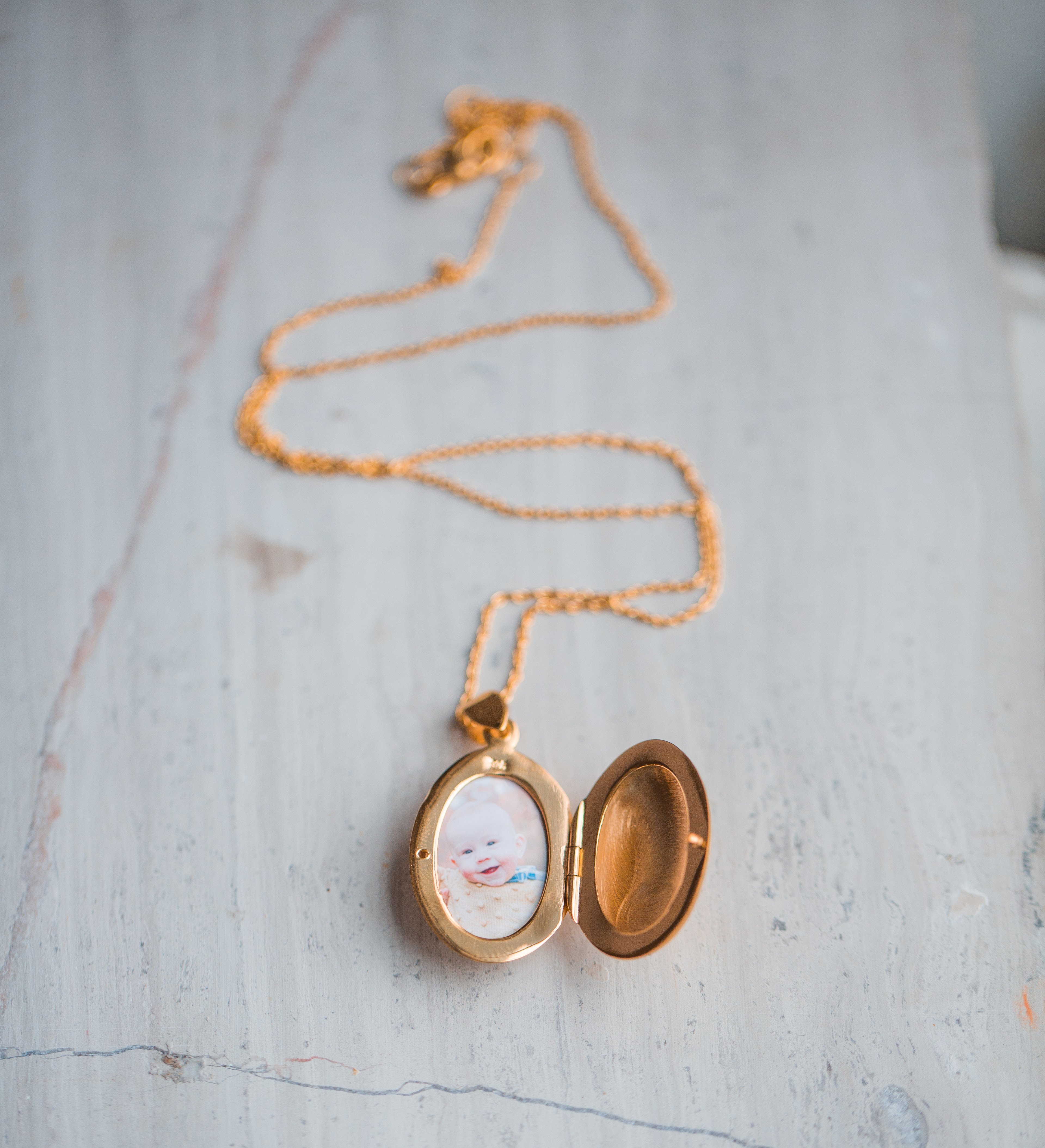 gold oval shaped locket with photo of little boy inside