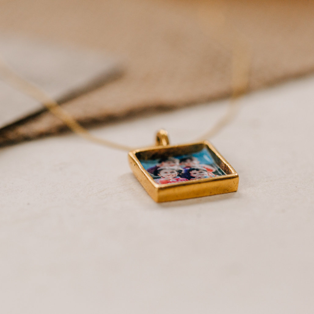 gold square pendant locket necklace with photograph placed inside under resin