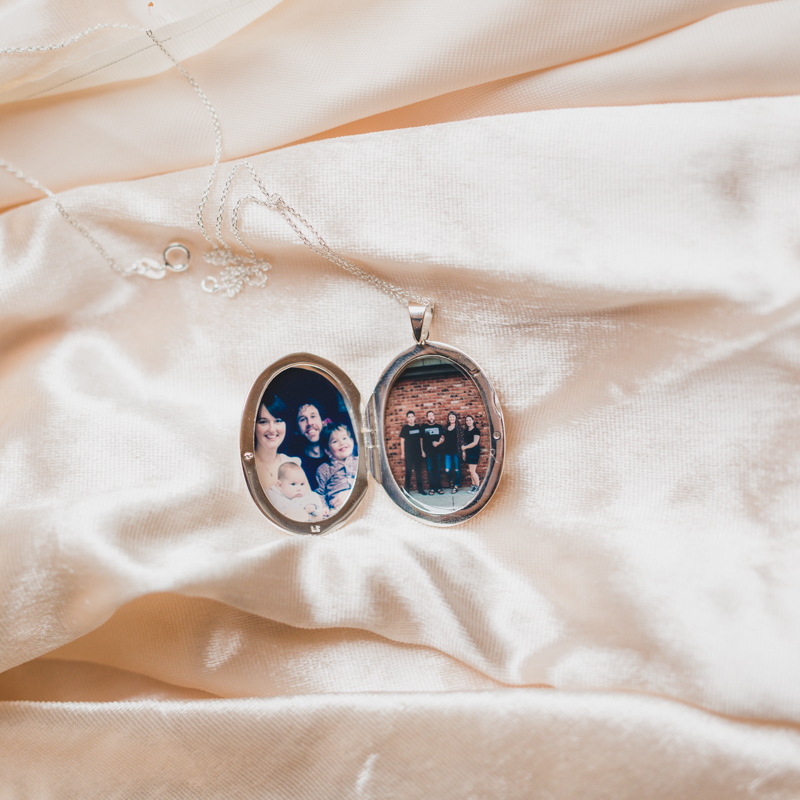silver oval locket called the evelyn with a photograph of her family and her husband under resin inside the locket itself placed inside by the locket sisters