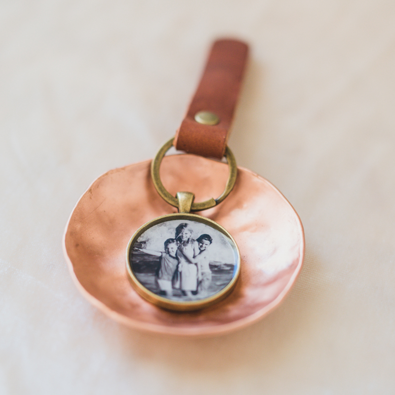 The Henry Locket is a bronze pendant with handcut leather keychain attached and a photo inside set safely under resin