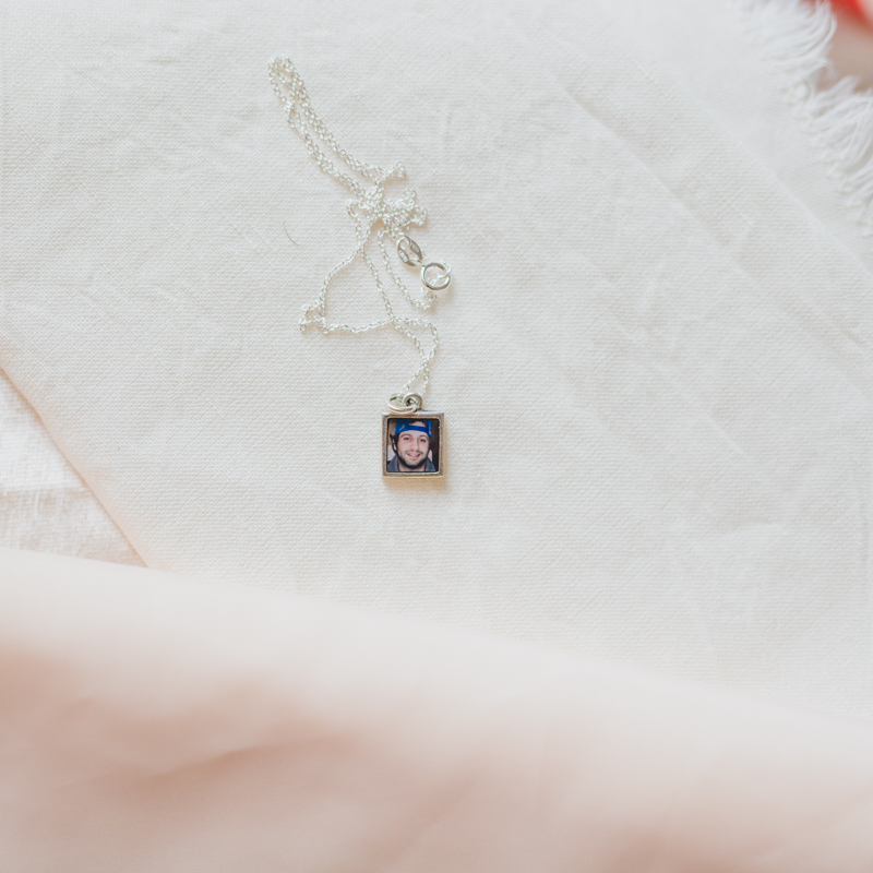 small square silver photo locket with picture under resin of her cousin who was killed in 2019