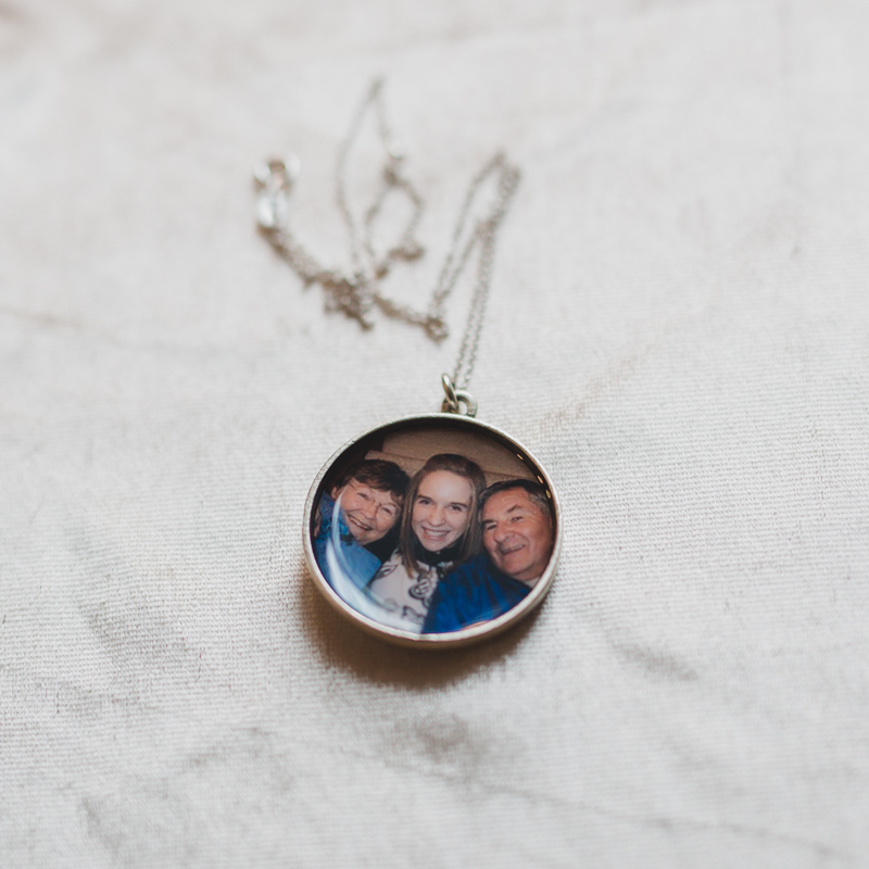 large round silver open locket pendant with photograph of three people set inside under resin