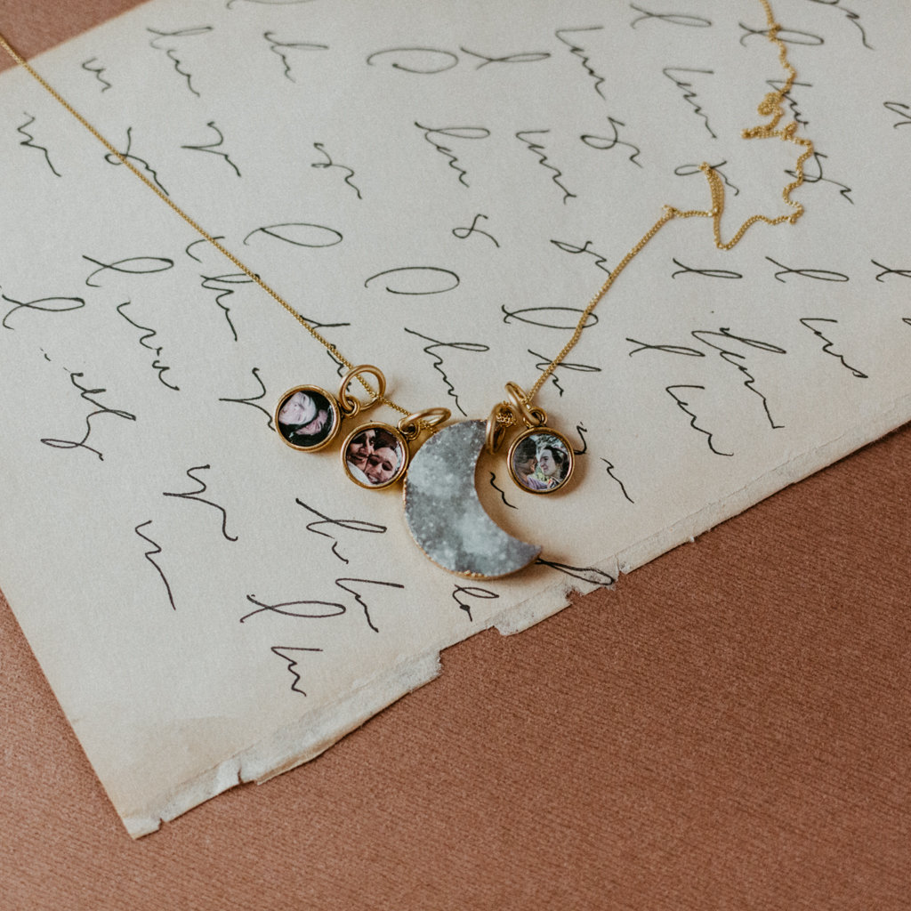 three small gold pendants with photographs inside on one chain with a grey druzy stone pendant for a locket necklace