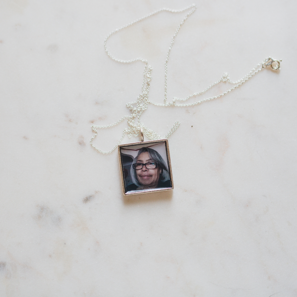 a silver square photo locket that keeps a once inch square photo inside under resin