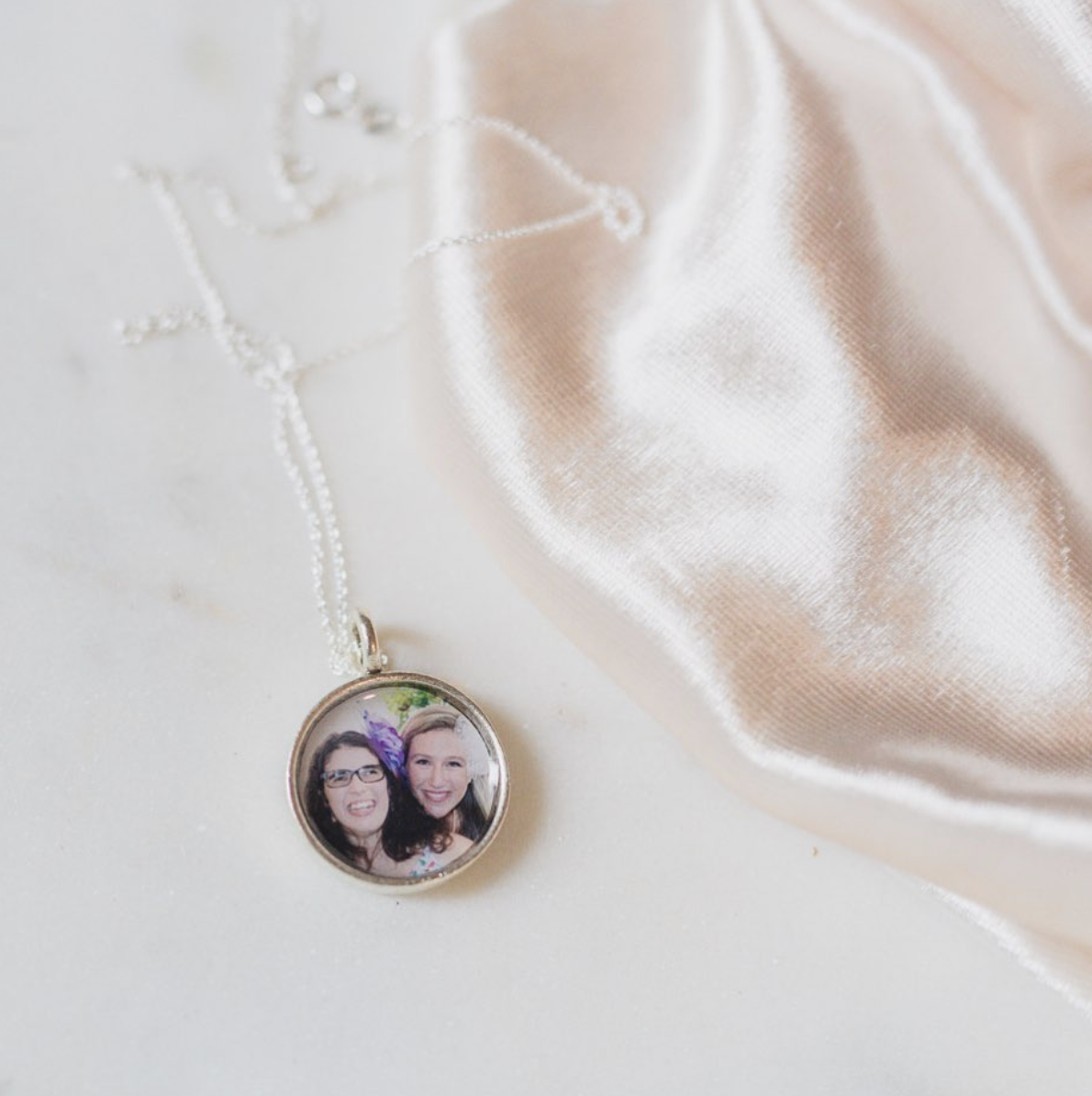 small silver pendant locket with photograph of sisters inside