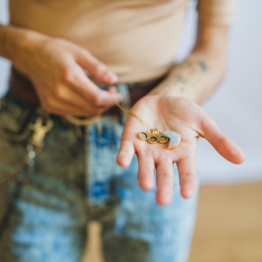 person holding grey druzy charm locket in hand